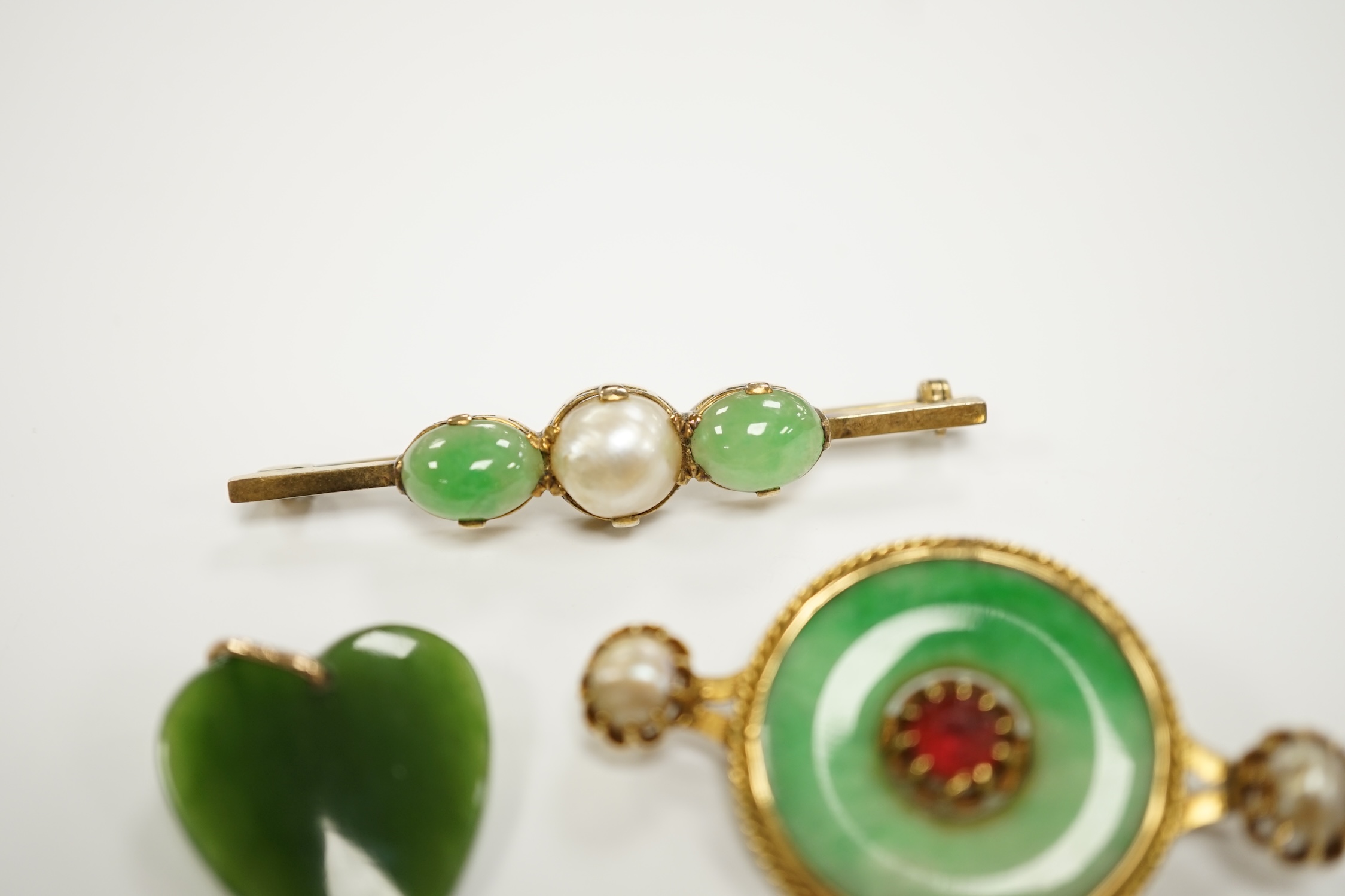 A Chinese 18k mounted, jade, cultured pearl and gem set disc brooch, 48mm, together with a yellow metal, jade and cultured pearl set bar brooch and a nephrite pendant.